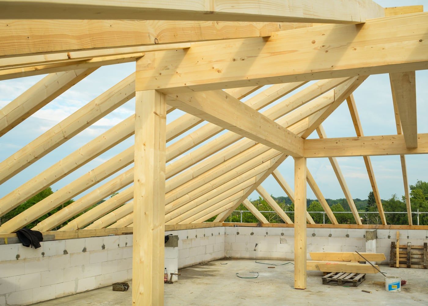 Fertig aufgerichteter Dachstuhl aus Holz über einem Rohbau, dahinter der Himmel