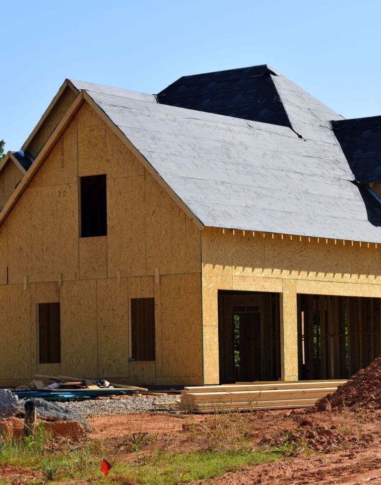 Rohbau eines Holzhauses mit fertigem Dachstuhl auf einem Grundstück